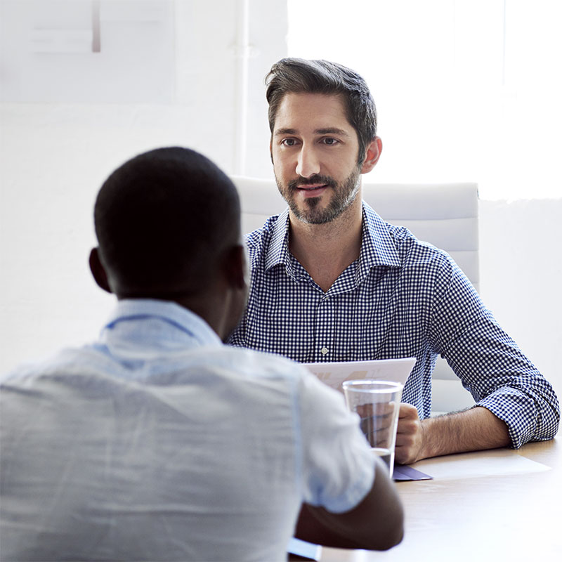 Two men engaging in a conversation during a hiring process, illustrating professional recruitment steps and candidate assessment.